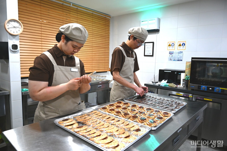 우윤화(왼쪽), 우승환 제과제빵사가 자신들이 구운 쿠기에 유통기한 도장과 상태 등을 검수하고 있다.